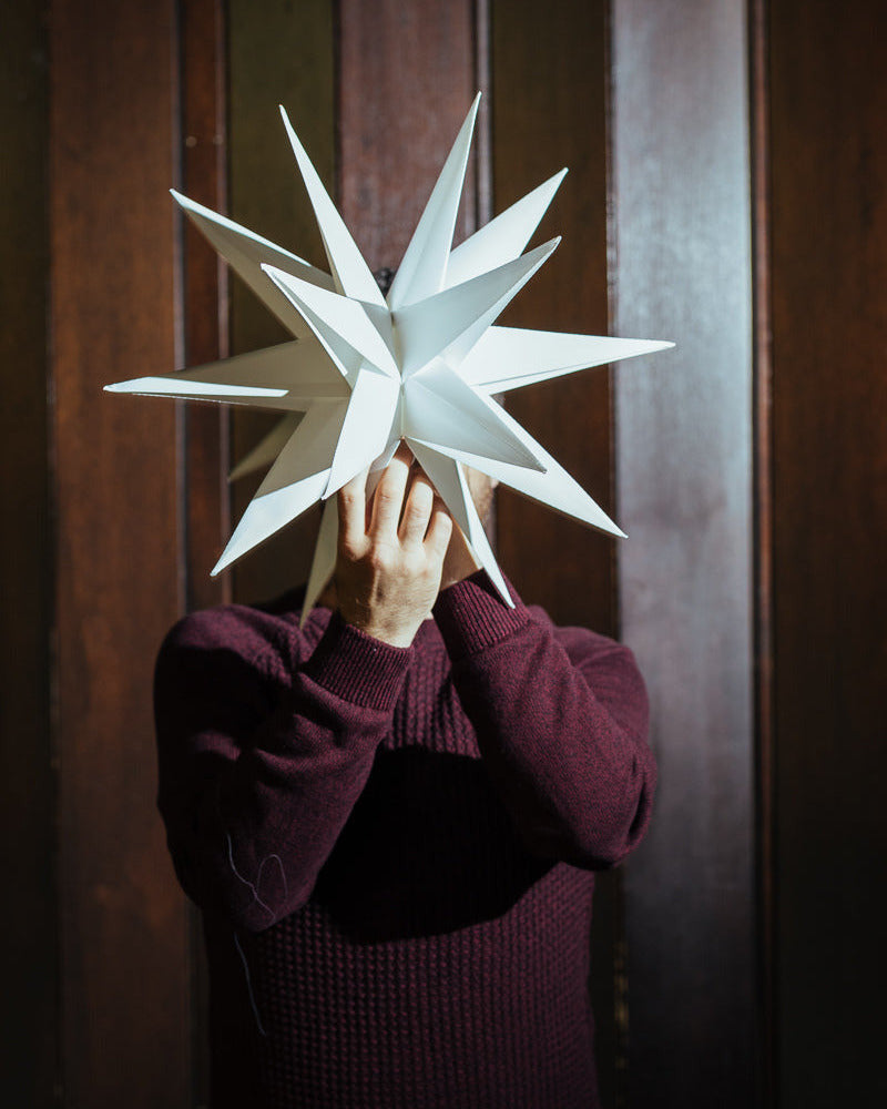 Portrait of Richard Resch holding a christmas star in front of his face.