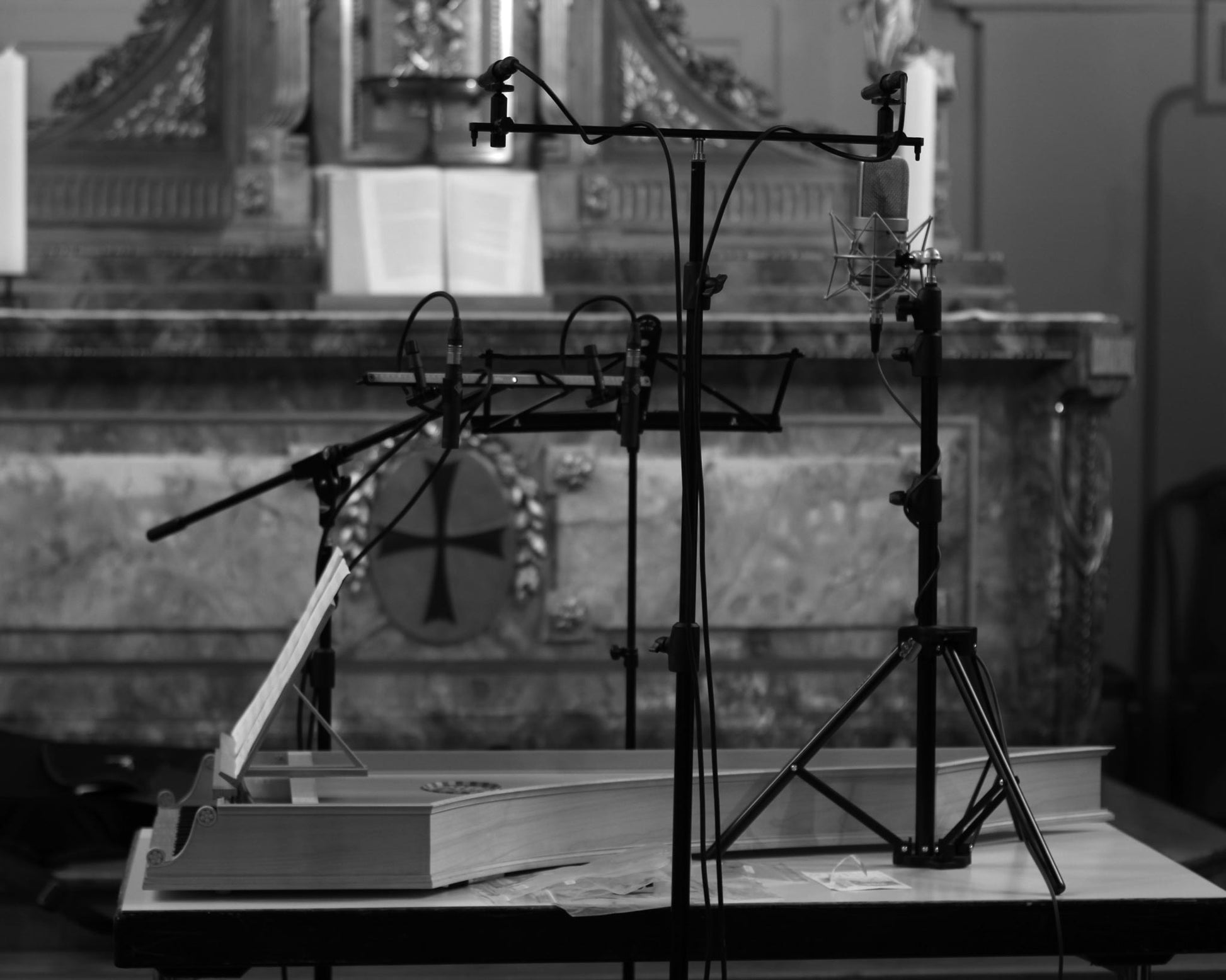 Microphone stand with multiple microphones around a harpsichord on a table in a church with decorative elements.