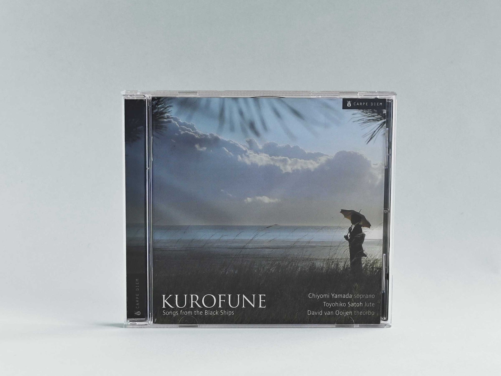 Jewelcase cover of the album "Kurofune" by Chiyomi Yamada saying "Songs from the black ships" and showing the artist with a Japanese umbrella at a seaside scenery.